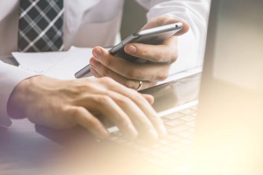 Işık tonlama, kahve içme ve evde dizüstü bilgisayar ve mobil akıllı telefon kullanarak iş adamı, Genç adam telefon, e ticaret veya evden online çalışan Internet tarama