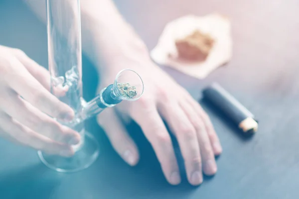 De handen van een man op de Bong en medische marihuana, cannabis thc flower Sativa en Indica close-up op een zwarte achtergrond. lifestyle concepten de legalisatie van marihuana licht toning — Stockfoto