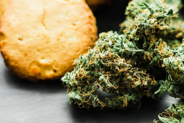 Makro knopp cannabis Cookies och knoppar av marijuana på bordet. En burk med cannabis knoppar begreppet matlagning med cannabisblad. Behandling av medicinsk marijuana för användning i livsmedel, på en svart bakgrund — Stockfoto