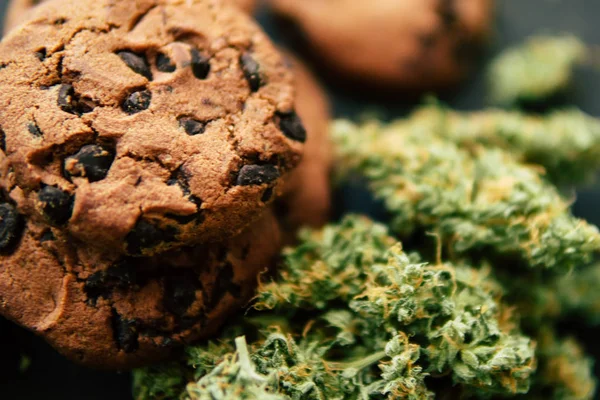 Conceito de cozinhar com erva de cannabis. Tratamento de maconha medicinal para uso em alimentos, Em um fundo preto Cookies com cannabis e botões de maconha na mesa . — Fotografia de Stock