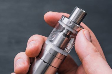 Vaping aygıt arka plan bir mod, duman püf noktalarını kullanarak vape elektronik sigara bulut vape genç adam.