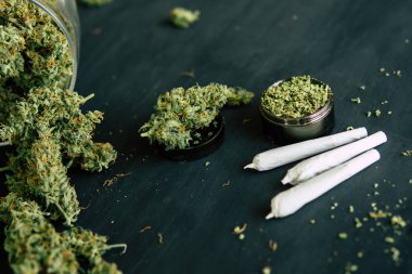 esrar ortak ve bir ot siyah ahşap üzerine esrar esrar tomurcuk çiçekler arka plan. kıyma ve rendelenmiş