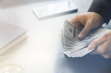 Beyaz genç işadamı para sayar 100 doları ışık tonlama