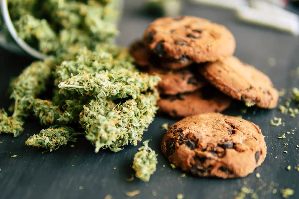 Cozinhar com cannabis Cookies com cannabis e botões de maconha na mesa. Copiar espaçoConceito de erva. Tratamento de maconha medicinal para uso em alimentos, em um fundo preto de perto — Fotografia de Stock