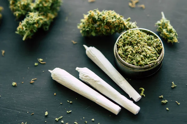 Cannabis toppen marihuana met schubben en geplette onkruid op een zwarte tafel dicht omhoog Joint onkruid Macro van — Stockfoto