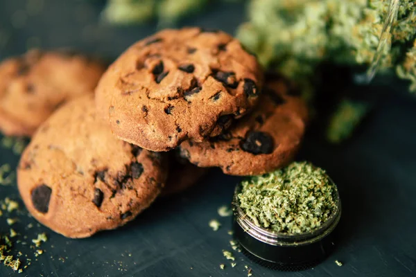 Begreppet matlagning med cannabisblad. Behandling av medicinsk marijuana för användning i livsmedel, på en svart bakgrund Cookies med cannabis och knoppar av marijuana på bordet. — Stockfoto