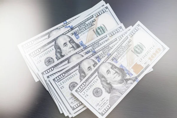 Bize yeni bir siyah Ahşap dokulu masaya yüz dolarlık banknotlar. Işık tonlama