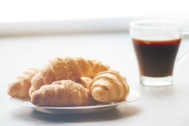 Kahve fincanı ve taze pişmiş kruvasanlar ahşap arka plan üzerinde. Işık tonlama üstten görünüm