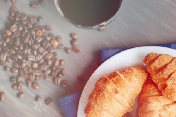 Kaffeetasse und frisch gebackene Croissants auf Holzuntergrund. Draufsicht, leichte Straffung — Stockfoto