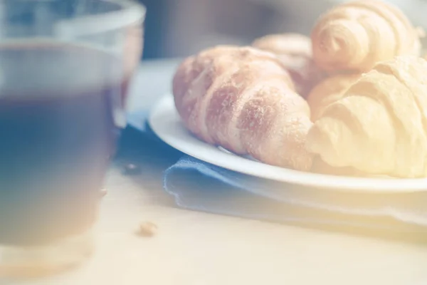 Coffee cup and fresh baked croissants on wooden background. Top , light toning — Stock Photo, Image