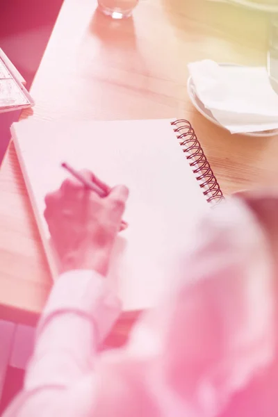 Business, education, planning and people concept - close up of female hands with pencil, coffee and cookies drawing scheme to notebook on table, light toning — Foto de Stock