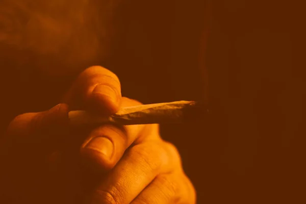 Un hombre fuma marihuana, un porro y un encendedor en sus manos. Tonificación amarilla — Foto de Stock