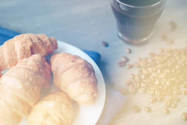 Kaffeetasse und frisch gebackene Croissants auf Holzuntergrund. oben, leichte Tonung — Stockfoto