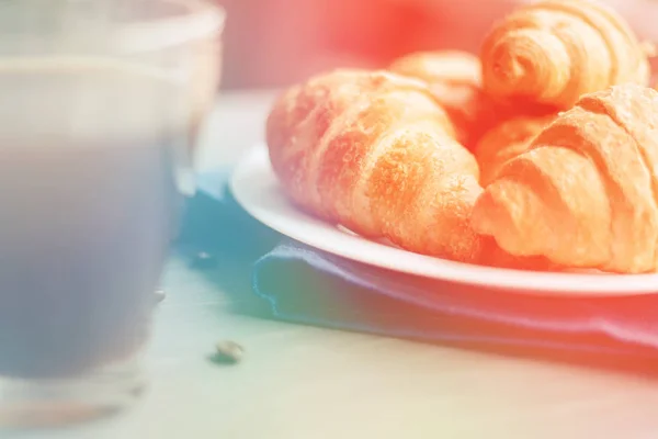Coffee cup and fresh baked croissants on wooden background. Top , light toning — Stock Photo, Image