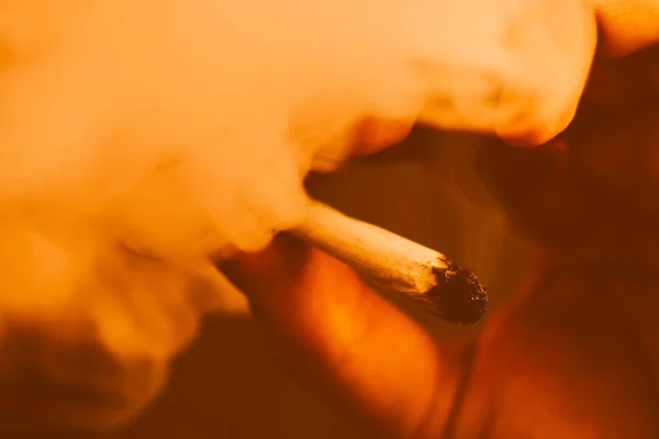 大麻杂草一个人抽烟, 一个关节和他手中的打火机。黄色色调 — 图库照片