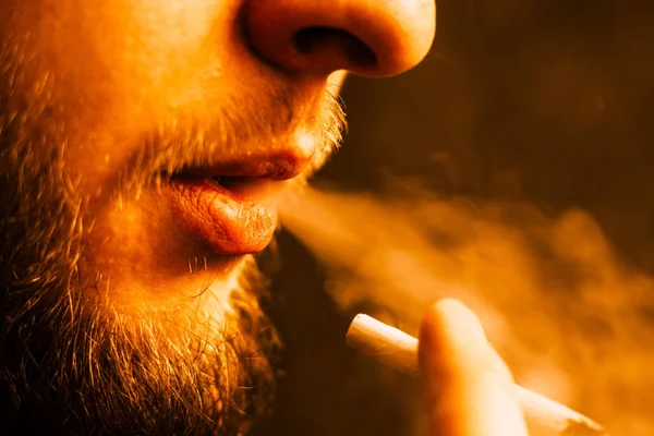 一个男人吸食大麻大麻, 一个关节和他手中的打火机。光色调 — 图库照片