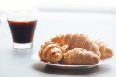 Kahve fincanı ve taze pişmiş kruvasanlar ahşap arka plan üzerinde. Işık tonlama üstten görünüm