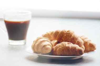 Kahve fincanı ve taze pişmiş kruvasanlar ahşap arka plan üzerinde. Işık tonlama üstten görünüm