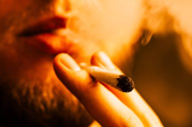 Sigara ve esrar esrar, esrar ve onun elinde bir çakmak. Sarı tonlama duman