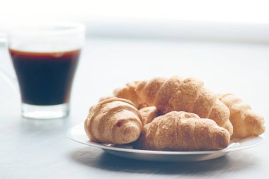 Kahve fincanı ve taze pişmiş kruvasanlar ahşap arka plan üzerinde. Işık tonlama üstten görünüm