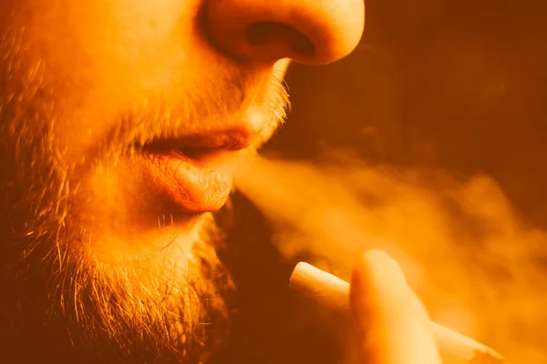 男は、彼の手で大麻雑草、ジョイントとライターを吸います。黄色の調子を整える — ストック写真