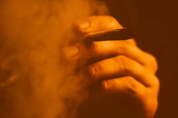 Um homem fuma erva de cannabis, um charro e um isqueiro nas mãos. Tonificação amarela, tonificação amarela — Fotografia de Stock