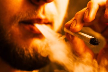 Bir adam sigara esrar esrar, esrar ve çakmak elinde. Sarı tonlama