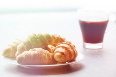 Kahve fincanı ve taze pişmiş kruvasanlar ahşap arka plan üzerinde. Işık tonlama üstten görünüm