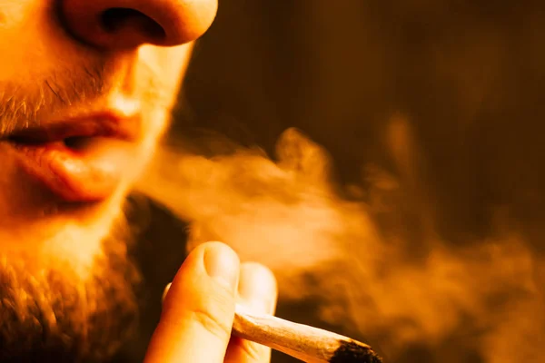 大麻杂草, 在他手中的一个男人抽烟的联合。黄色色调的烟雾 — 图库照片