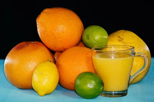 Frutas de citrinos, laranja, limão, limão, pomelo, toranja com suco de laranja em um copo de vidro — Fotografia de Stock