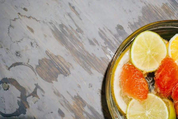 Cítricos en agua con burbujas en plato transparente Naranjas, limones, grisáceas, limonada Pamela Espacio para firma sobre textura de madera — Foto de Stock