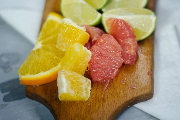 Pile de tranches d'agrumes. Oranges et citrons limes, pamplemousse, pomelo. Sur table en bois — Photo