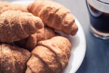Tatlı ve kahve. Moody renk dostum. Makro vurdu. Amerikan kahve ve siyah bir zemin üzerine taze kruvasanlar. Kahvaltı kavramı.