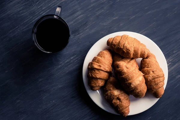 Mate moody color. American coffee and fresh croissants on a black background. Dessert and coffee. The concept of breakfast. Macro shot. — Stock Photo, Image