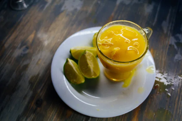 Ein Glas Orangensaft mit einem großen Spritzer und Limette auf einem Teller — Stockfoto