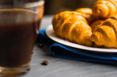 Kahvaltı kavramı. Tatlı ve kahve çekirdekleri. Makro çekim taze kruvasan ve kahve siyah bir arka plan. Dostum moody renk.