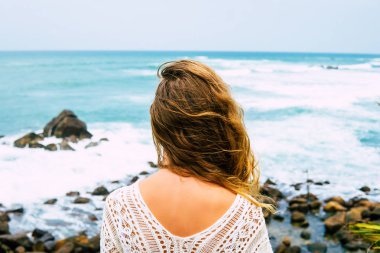 Kayalık sahilde poz uzun saçlı çekici sarışın kız portresi. O bikini, şapka, güneş gözlüğü takıyor. Gülümsüyor. Broidered Sri Lanka