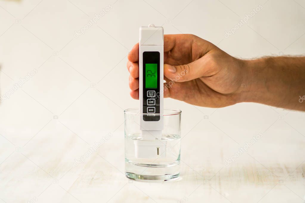 A hand with a TDS measuring instrument. Good indicators of drinking water. Soft water. Tap drinking water quality control showing a high level of TDS Total dissolved solids