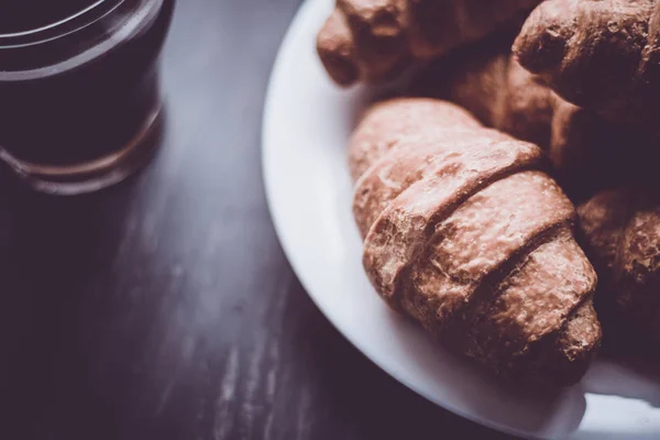 Macro shot. American coffee and fresh croissants on a black background. The concept of breakfast. Mate moody color. Dessert and coffee. — Stock Photo, Image