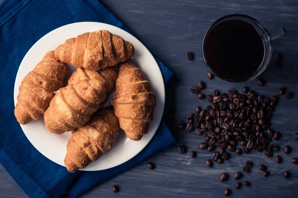 Färska croissanter och kaffe på en svart bakgrund. Makro skott. Begreppet frukost. Dessert och kaffe. Mate lynnig färg. Ovanifrån . — Stockfoto