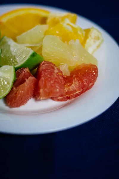 stack of citrus fruits slices. Oranges and lemons limes, grapefruit, pomelo. on a white plate