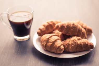 Tatlı ve kahve. Moody renk dostum. Yakın çekim. Amerikan kahve ve siyah bir zemin üzerine taze kruvasanlar. Kahvaltı kavramı.