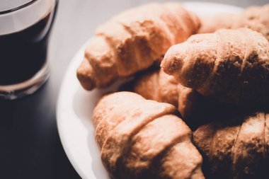 Kahvaltı kavramı. Tatlı ve kahve. Moody renk dostum. Makro vurdu. Amerikan kahve ve siyah bir zemin üzerine taze kruvasanlar.