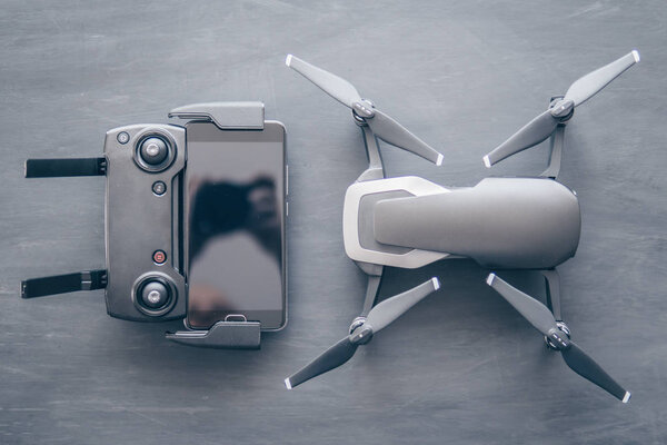 A new black drone on a black table. The concept of using drones in life and industry. Top view Remote and smartphone macro Details. Copy space. Innovation photography concept. Mate color.