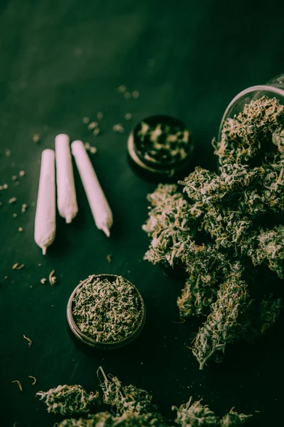 Amoladora con flores de cannabis trituradas y articulación y maleza en el tono verde malhumorado —  Fotos de Stock