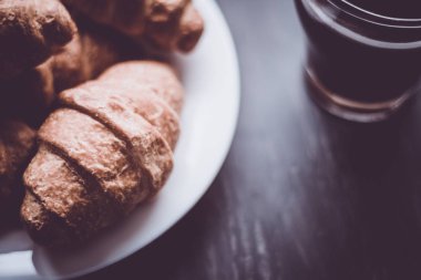 Tatlı ve kahve. Moody renk dostum. Makro vurdu. Amerikan kahve ve siyah bir zemin üzerine taze kruvasanlar. Kahvaltı kavramı.