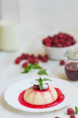 Dikey vurdu. Yaz tatlı. Açık renkli. Yakın çekim. Uçan pudra şekeri. Ahududu ve nane ile panakota.