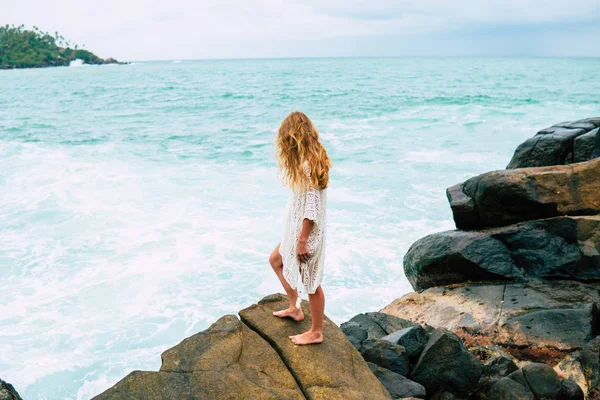 Menina bonita na praia com pedras grandes. A menina está posando perto do Surf do oceano. Feliz Verão, férias. A rapariga está de férias. Uma figura feminina sexy. Cabelo encaracolado. Mirisa Sri Lanka — Fotografia de Stock