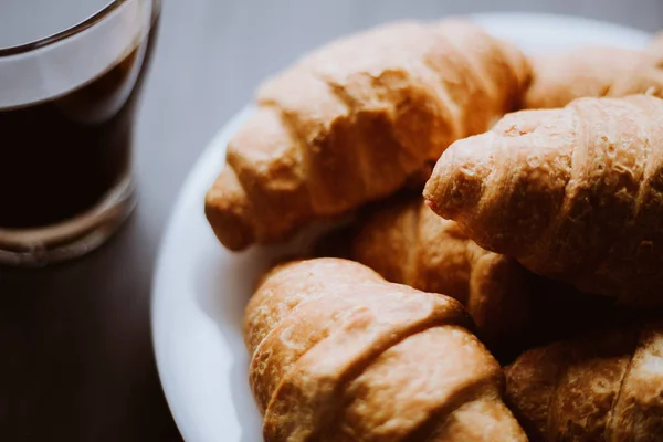 Amerikanischer Kaffee und frische Croissants auf schwarzem Hintergrund. das Konzept des Frühstücks. Dessert und Kaffee. Mate launische Farbe. Makroaufnahme. — Stockfoto