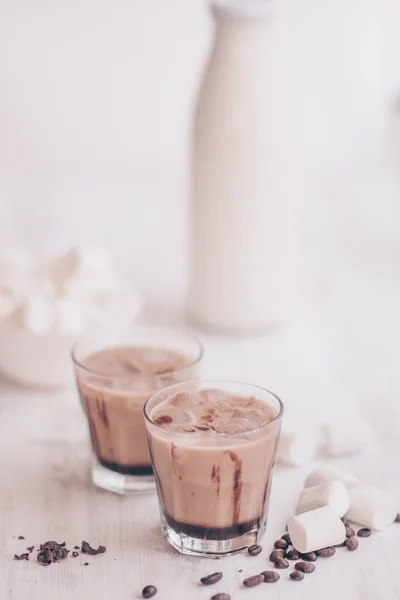 Café helado. Marshmelow y granos de café en la mesa. Concepto de bebida refrescante. Bebida de verano. Café frío con leche y chocolate. Disparo vertical. Fondo claro . — Foto de Stock